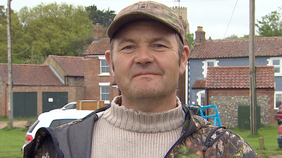 Gardener Jonathan Wright seen with cap and in front of a row of houses