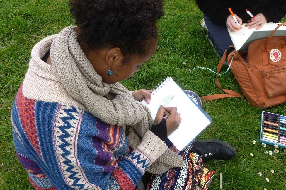 Jasmine Ibrahim sits drawing in a pad