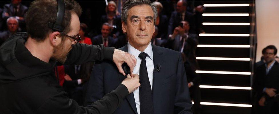 Francois Fillon (C) gets a microphone attached to his collar prior to the start of a debate of candidates organised by French private TV channel TF1 (20 March)