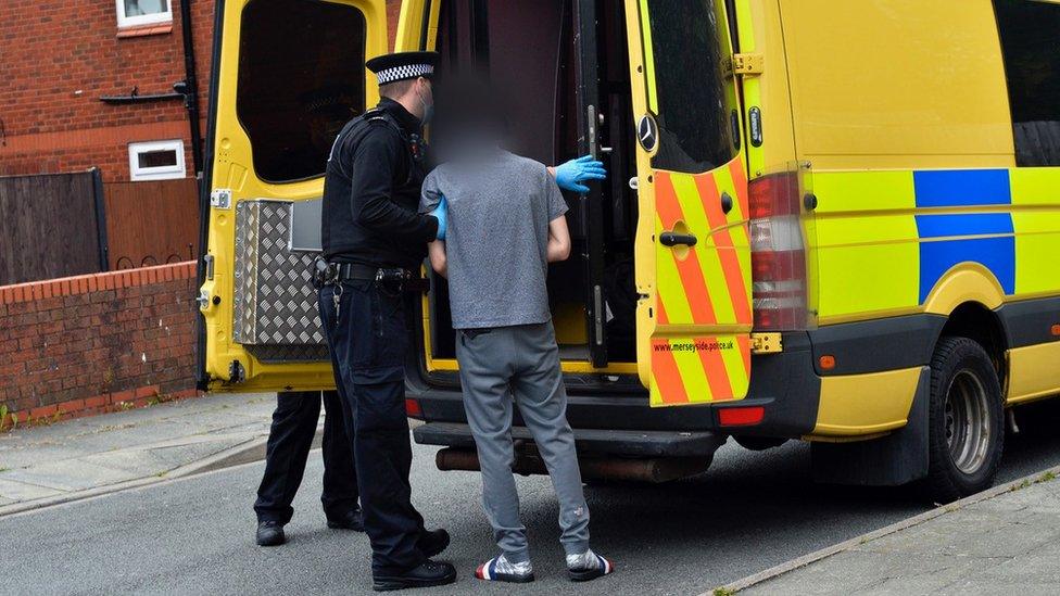 Suspect being put in a police van by officer