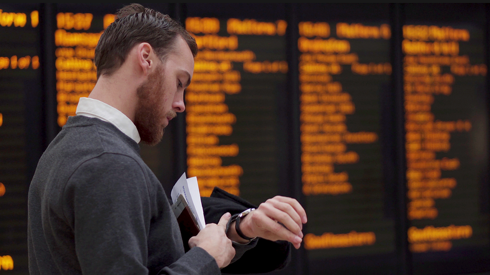 Man checks watch at train station