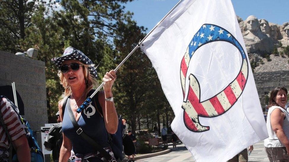 A Donald Trump supporter holding a QAnon flag visits Mount Rushmore National Monument on 01 July 2020