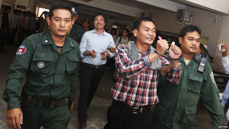 Supporters of the Cambodia National Rescue Party (CNRP), are escorted by Cambodian police officers at the Phnom Penh Municipal Court, 21 July 2015