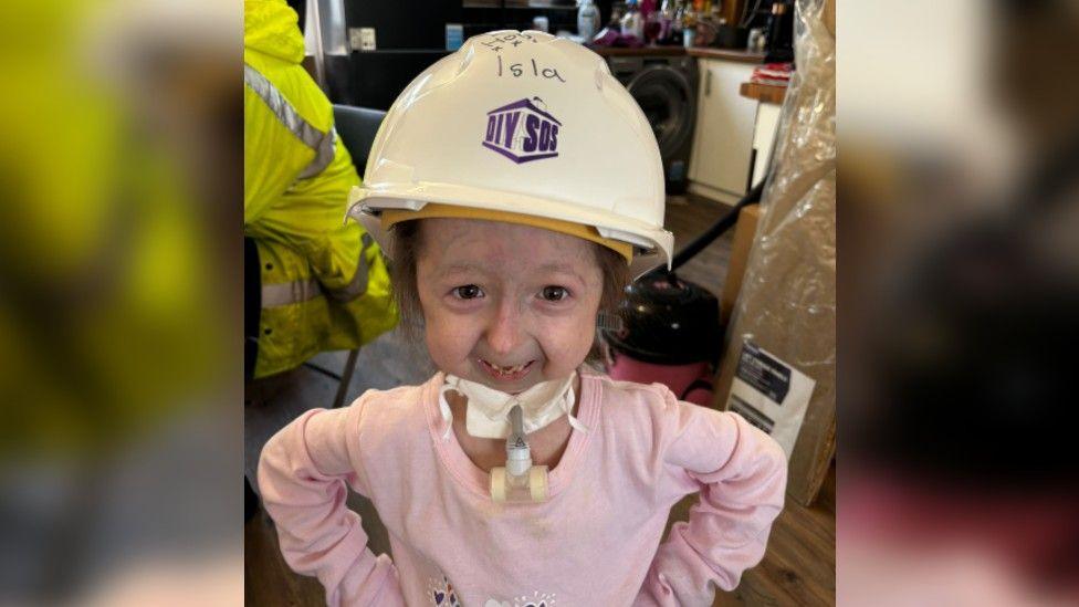 An image of Isla wearing a pink shirt and a DIY SOS hard hat