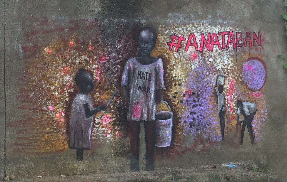 Child carrying a bucket wearing a t-shirt saying "I hate war"