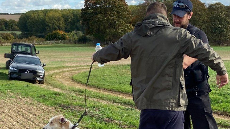 Police officer and man in a field with a dog