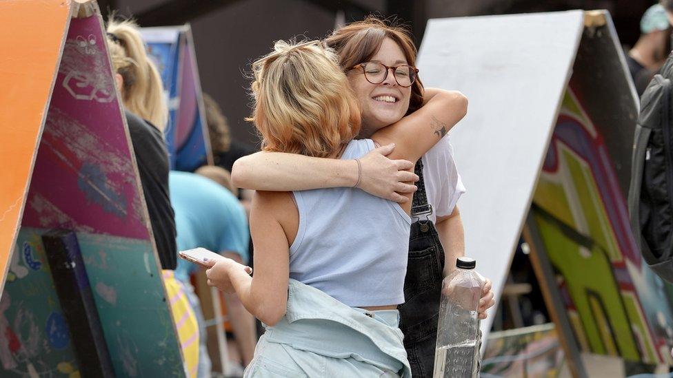 Two women who are painting canvases at Upfest Presents in Bristol embrace