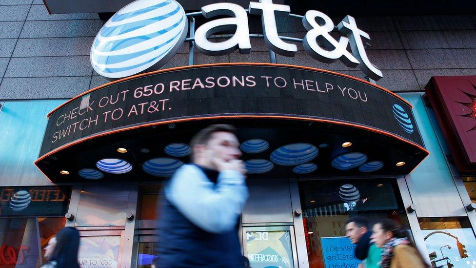 In this file photo taken on October 23, 2016 People walk past an AT^T store in New York.