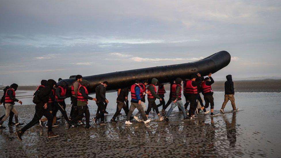 Migrants carrying boat to Dunkirk beach to cross channel to UK