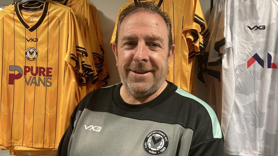 Newport County club secretary Gareth Evans standing in front of Newport shirts in the club shop