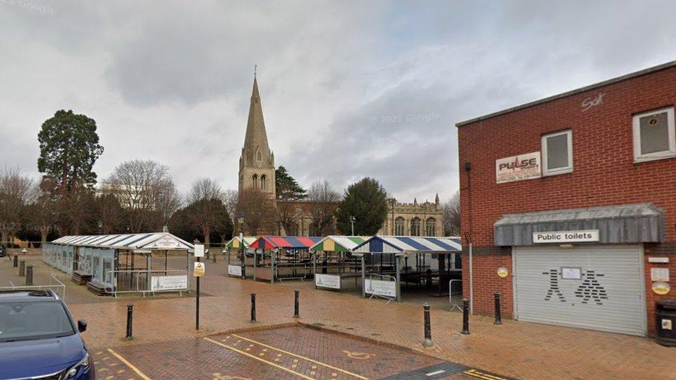 Metal market stalls with coloured roofs. A church is visible in the background.