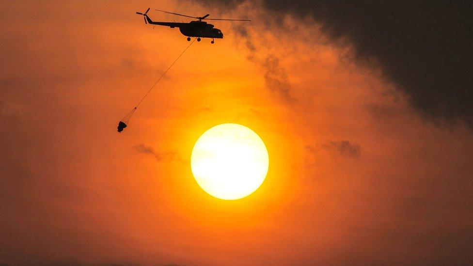 A helicopter carries water to extinguish a land fire in South Sumatra