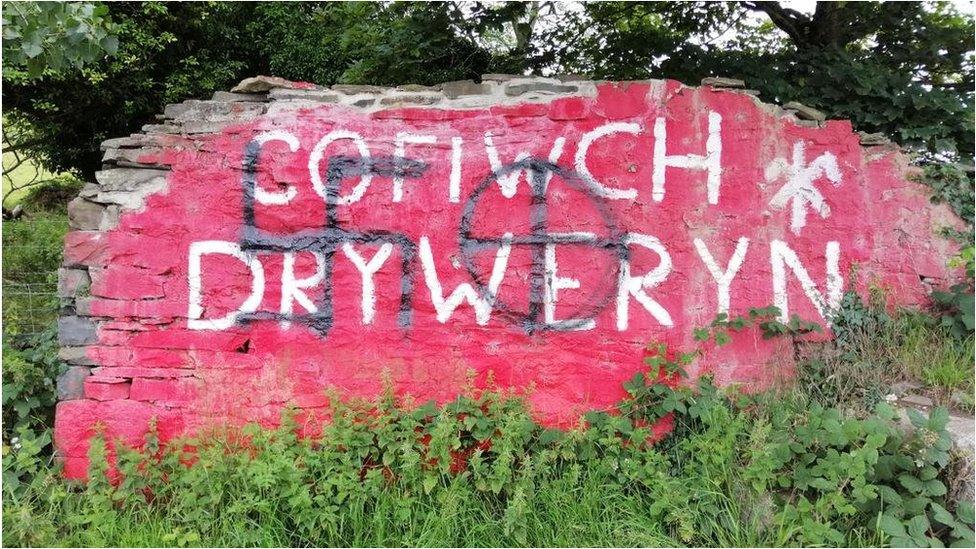 Wall showing the vandalism and painted swastika and cross