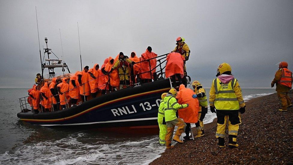 Migrants, picked up at sea attempting to cross the English Channel, are helped ashore from an Royal National Lifeboat Institution (RNLI) lifeboat, at Dungeness on the southeast coast of England, on December 9, 2022