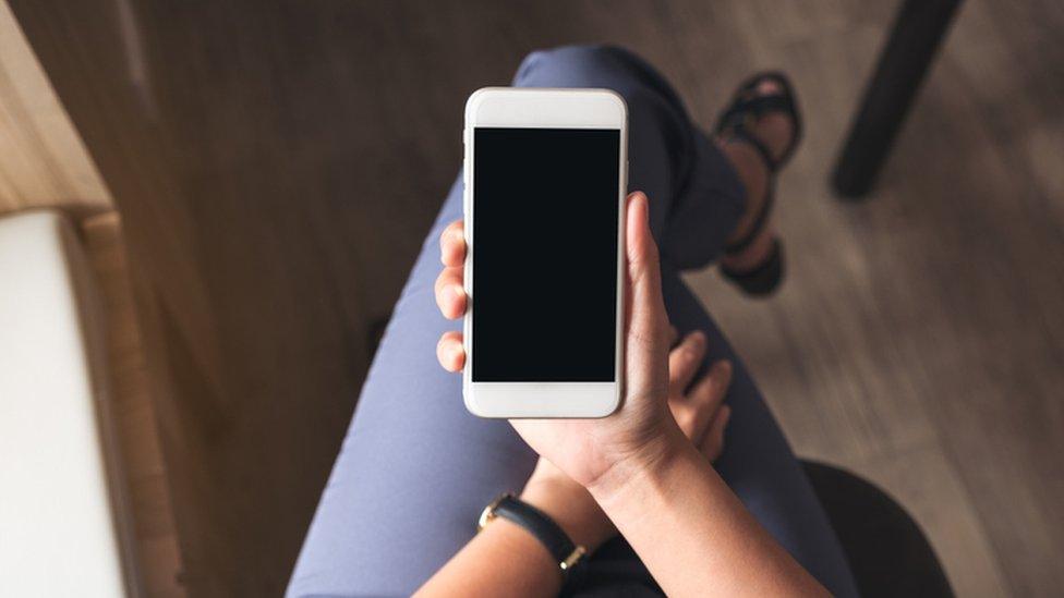 A woman holds a smart phone