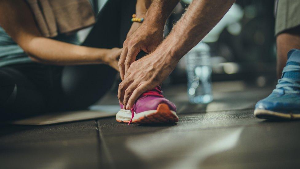 A male coach holds the ankle of a female athlete