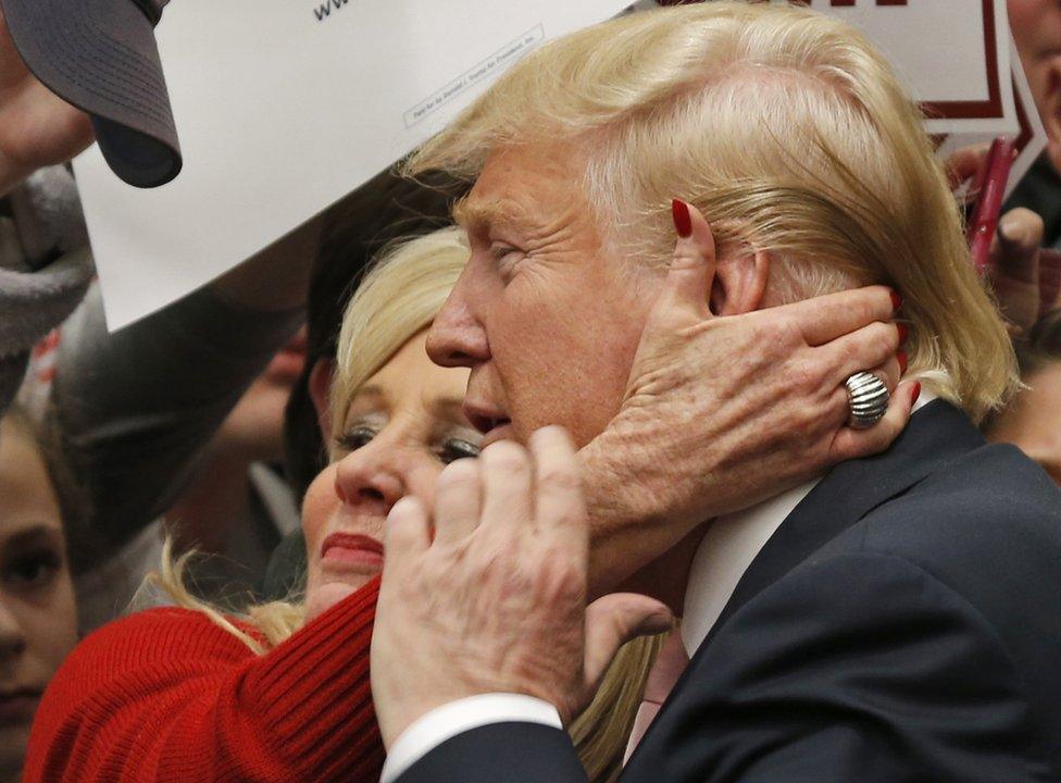 A supporter puts her hand to Donald Trump's face at a rally