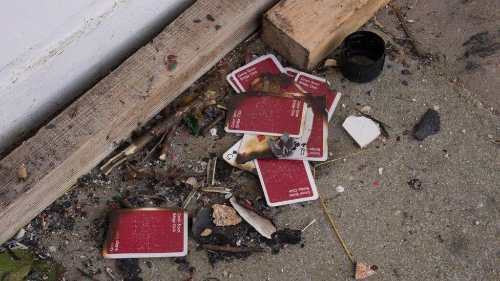 Playing cards that had been discarded after someone had tried to set to a board covering a window.