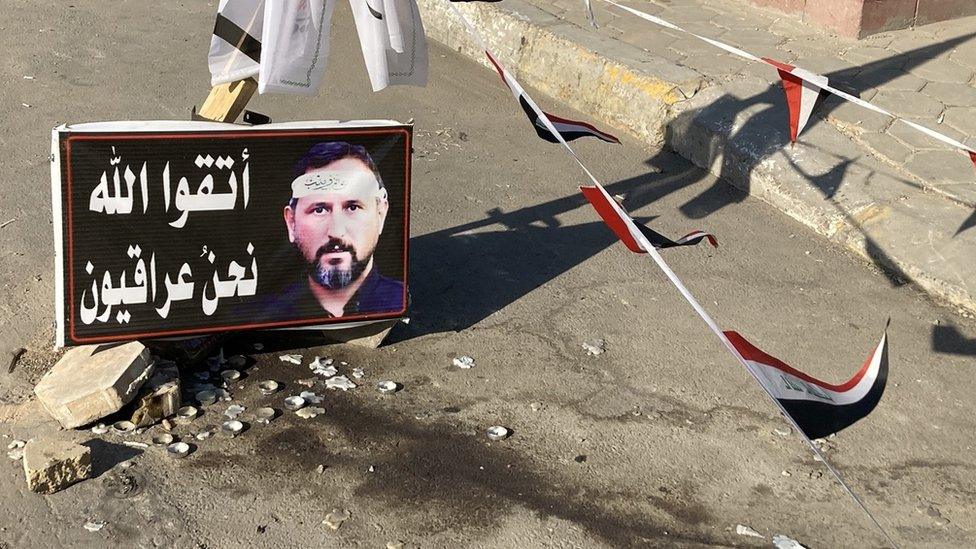 Flags and poster saying "Be mindful of Allah, we are Iraqis" marking spot where a supporter of an Iran-backed Iraqi Shia militia was killed by security forces at a protest against the election results in Baghdad, Iraq