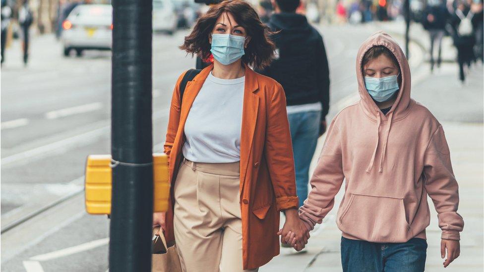 Mother and daughter walking on street with facemasks