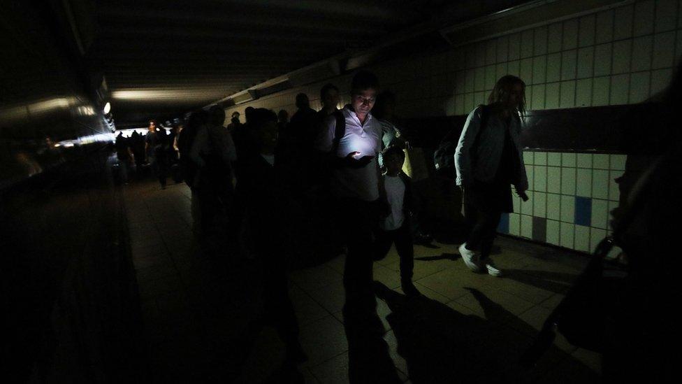 People walking in complete darkness at Clapham Junction station in London during a power cut,