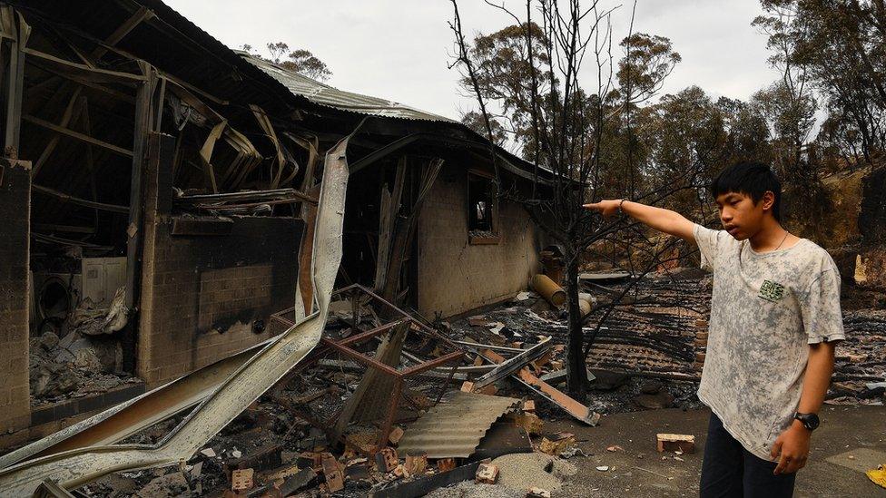 Gabriel points to his destroyed house