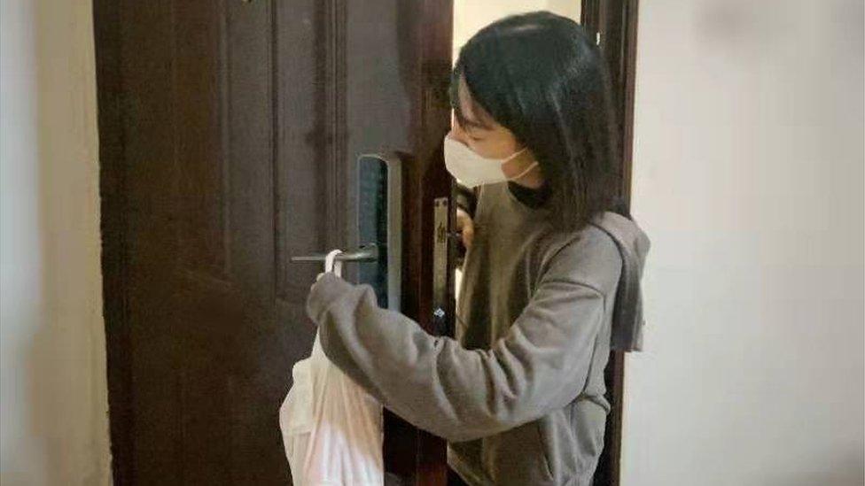 A woman takes delivery of food using contactless delivery