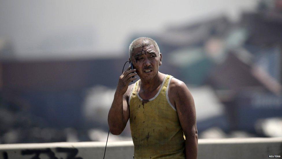 A survivor talk on his mobile phone at the site of the explosions at the Binhai new district in Tianjin August 13, 2015