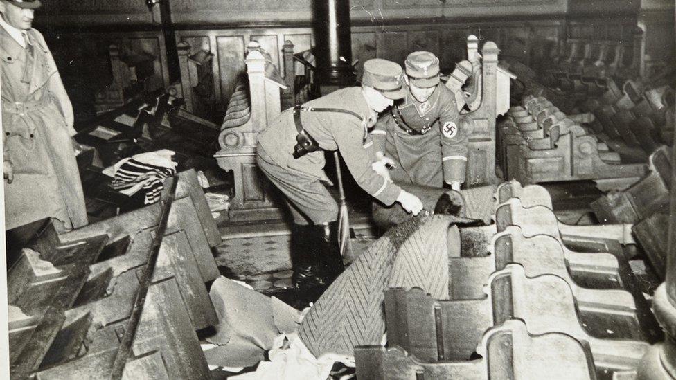 German forces pouring petrol onto pews at a synagogue