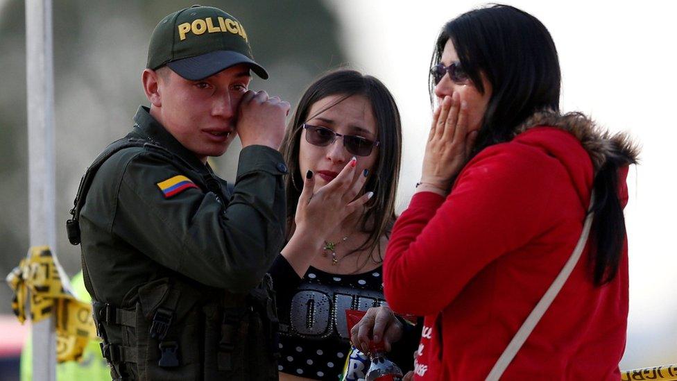 A police officer and two women wipe their tears close to the scene where a car bomb exploded