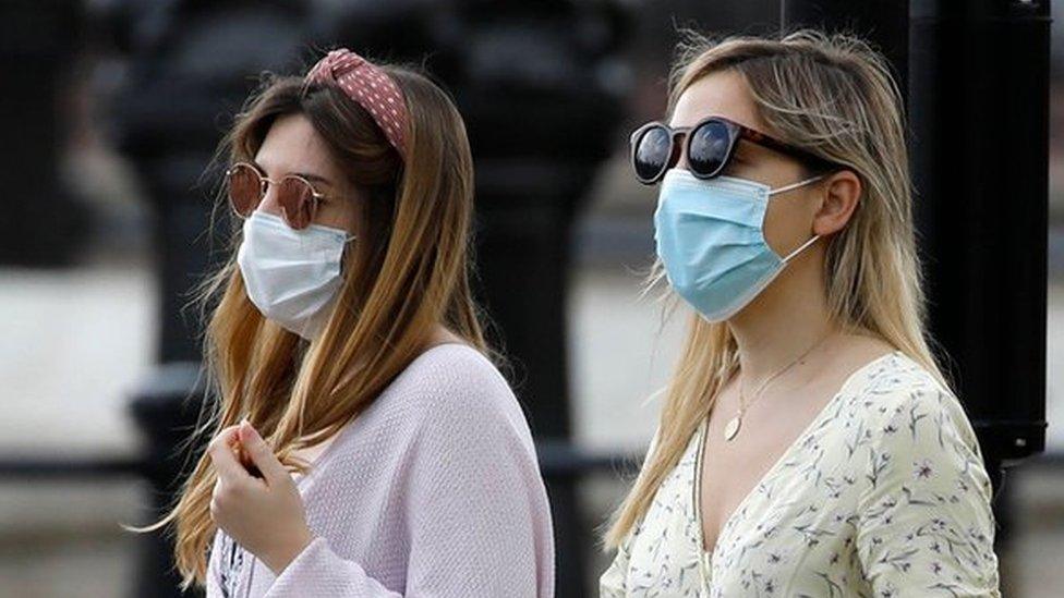 Two women walking wearing face masks