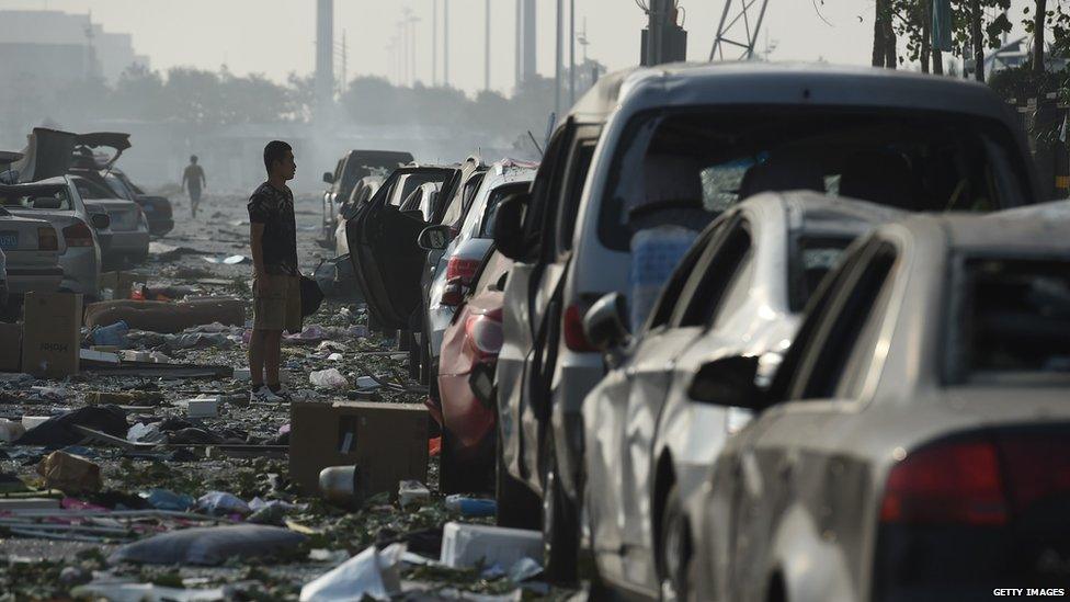 A man looks at a row of damaged cars outside a residential building near the site of a series of explosions in Tianjin, China