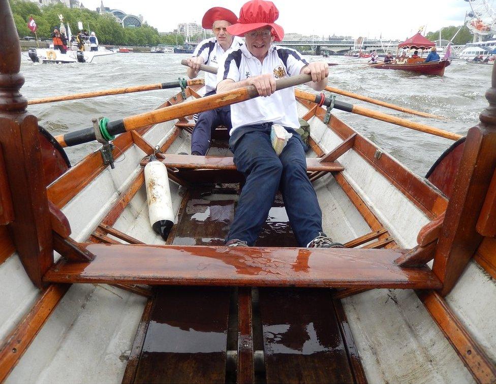 Two men are rowing a boat in a river