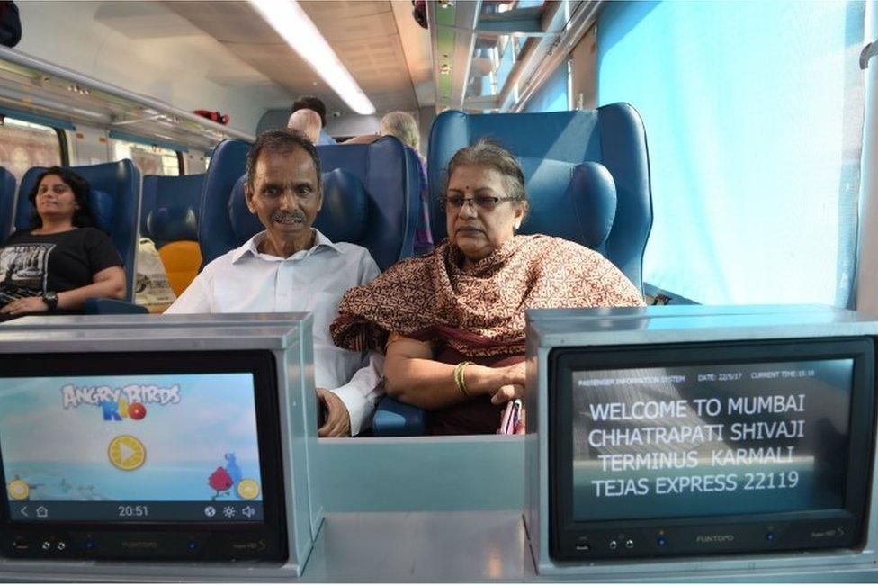 In this photograph taken on May 22, 2017, Indian passengers watch television screens onboard the Tejas Express luxury train during its first journey between Mumbai and Goa in Mumbai.