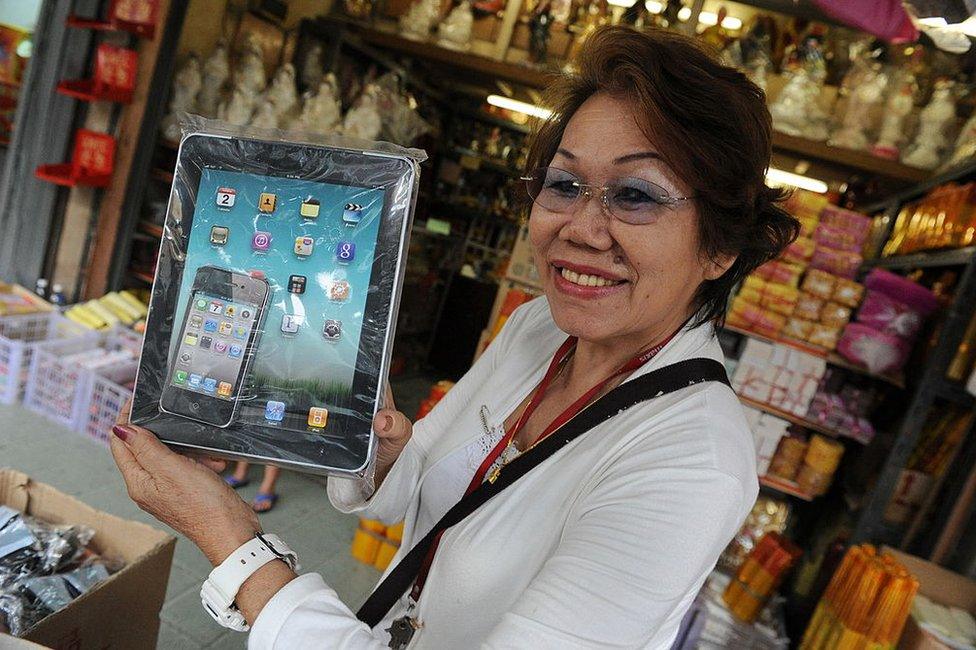 Shop owner Chow Kum Len shows off a paper replica iPad that is produced to be burnt as an offering to the dead during the Qing Ming festival in Kuala Lumpur on 6 April 2011