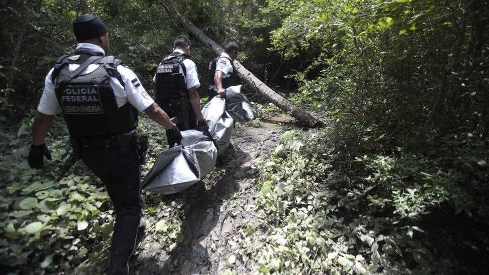 Federal Police officers carry one of the three corpses found in a clandestine grave at the Manuel Anorve neigbourhood in the municipality of Acapulco, Guerrero state, Mexico, on July 31, 2016.