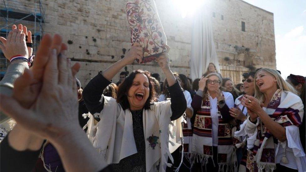 A member of the liberal Jewish religious movement "Women of the Wall" dances with a Torah scroll at the egalitarian prayer section on the southern side of Judaism's holiest prayer site of the Western Wall in the Old City of Jerusalem on 8 March 2019