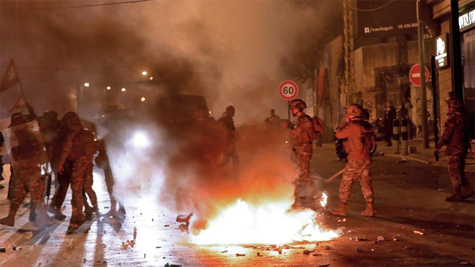 Lebanese soldiers surround a burning motorcycle amid clashes between supporters of the Hezbollah and Amal movements and anti-government protesters in Beirut on 25 November 2019