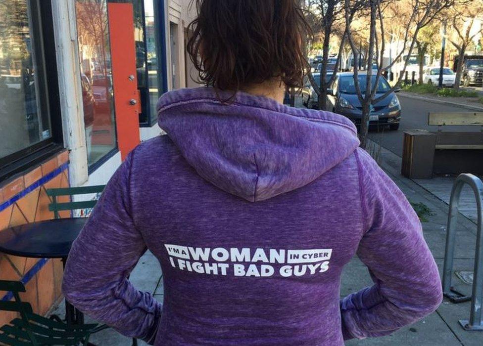 A woman wearing a jumper with the slogan 'I'm a woman in cyber. I fight bad guys'.