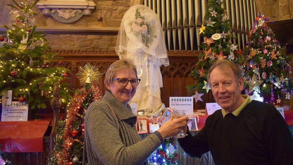 Linda and Paul Pearson celebrating their 38th wedding anniversary near the Post Alpha Home Group "tree" which features Linda's wedding dress