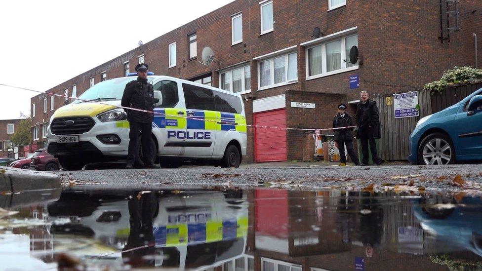 Police officer stands guard near a police car in the road