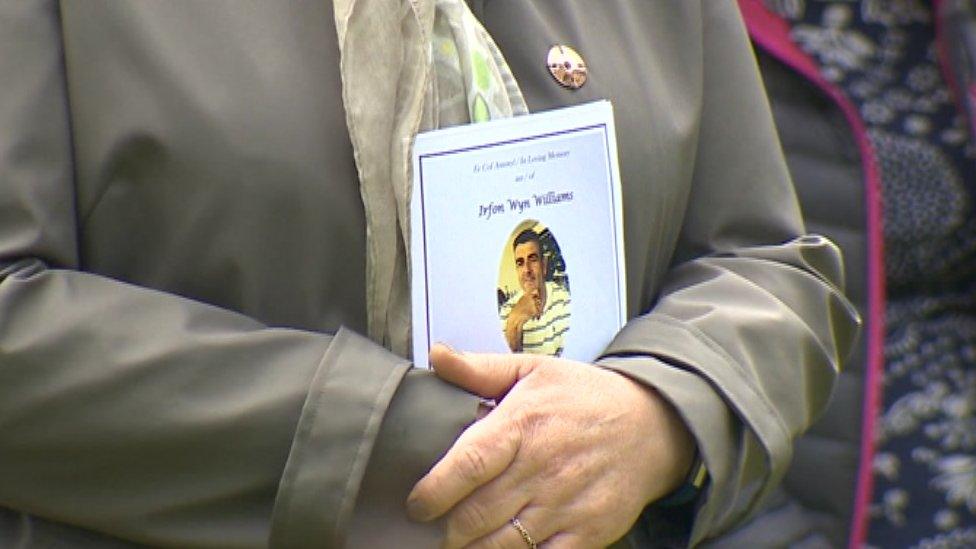 A mourner holds an order of service outside the funeral