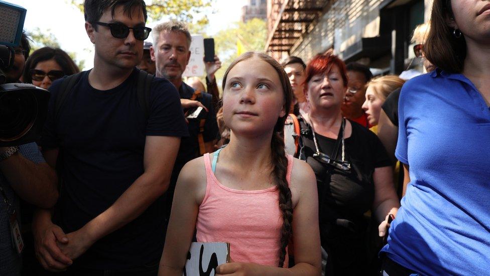 Greta walking through the streets of New york with people behind her