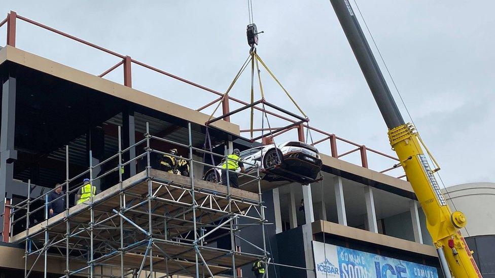 Car being hoisted up to the third floor of the nightclub