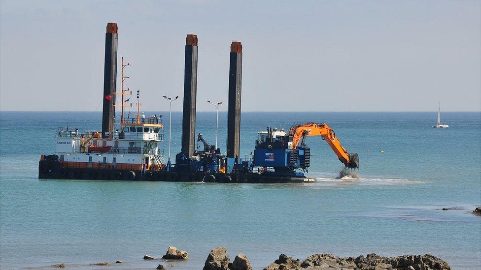 Floating platform with a digger working on the replacements for the sewage outfall pipes