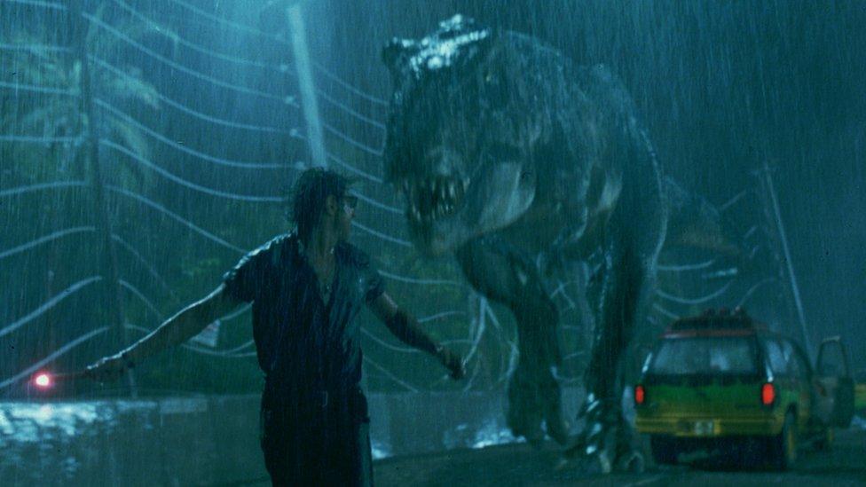 A scene from the film Jurassic Park - a man runs from a tyrannosaurus rex in the rain