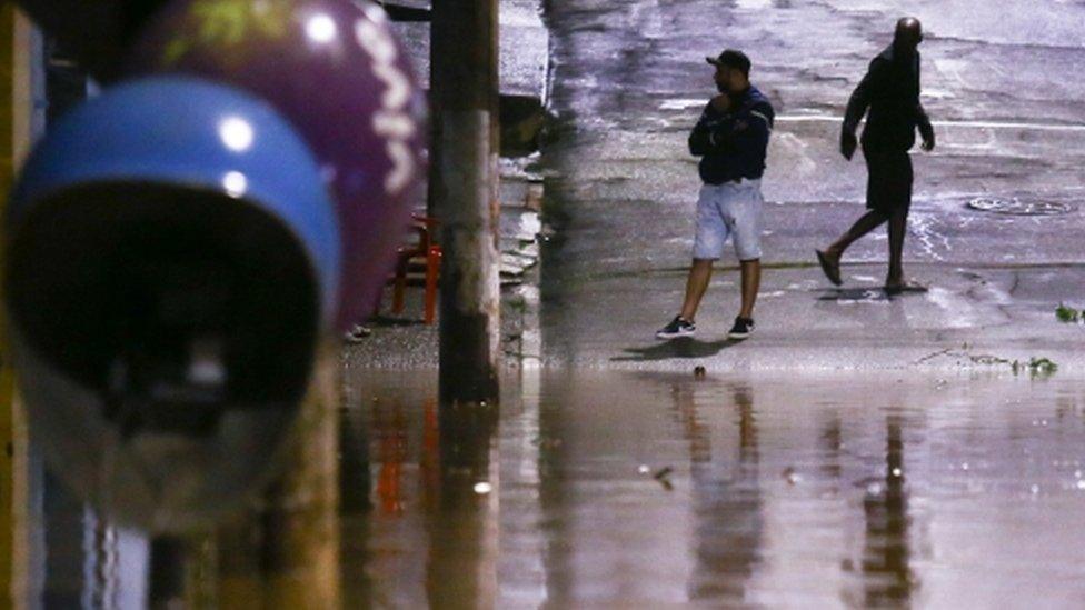 People stand in a flooded street after heavy rain in Caieiras, Brazil, 30 January 2022