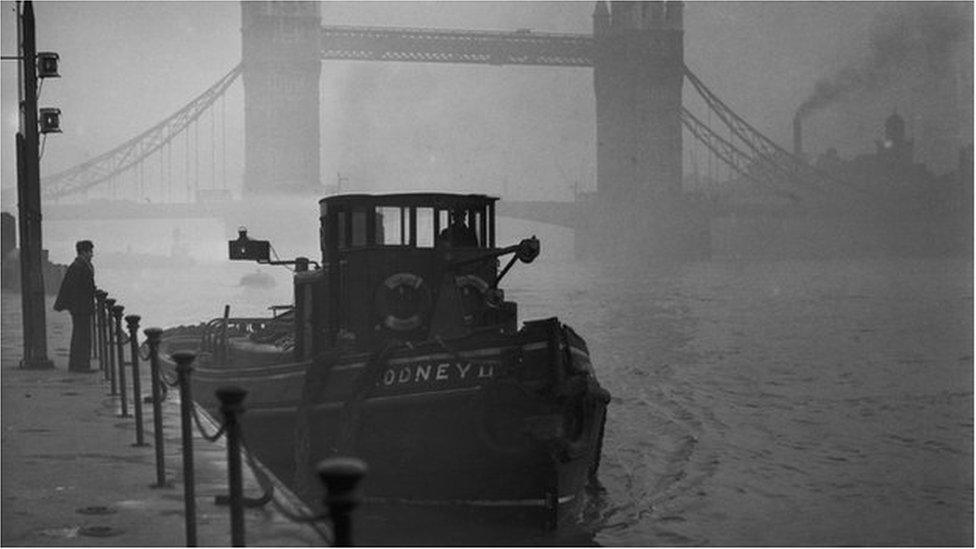 Tower Bridge peeps through a thick smog along the River Thames.