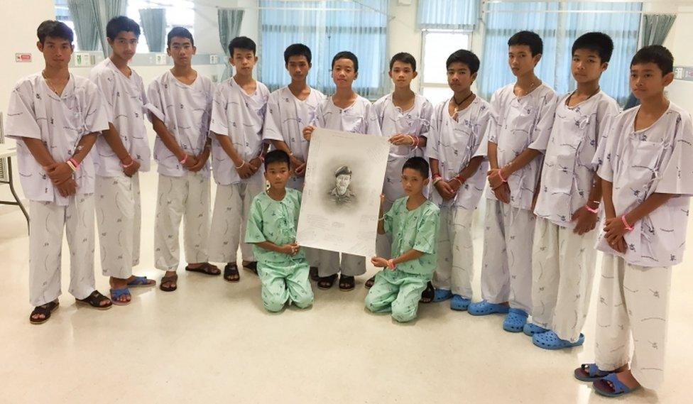 The 12-member "Wild Boars" soccer team and their coach rescued from a flooded cave pose with a drawing picture of Samarn Gunan, a former Thai navy diver who died working to rescue them, at Chiang Rai Prachanukroh Hospital