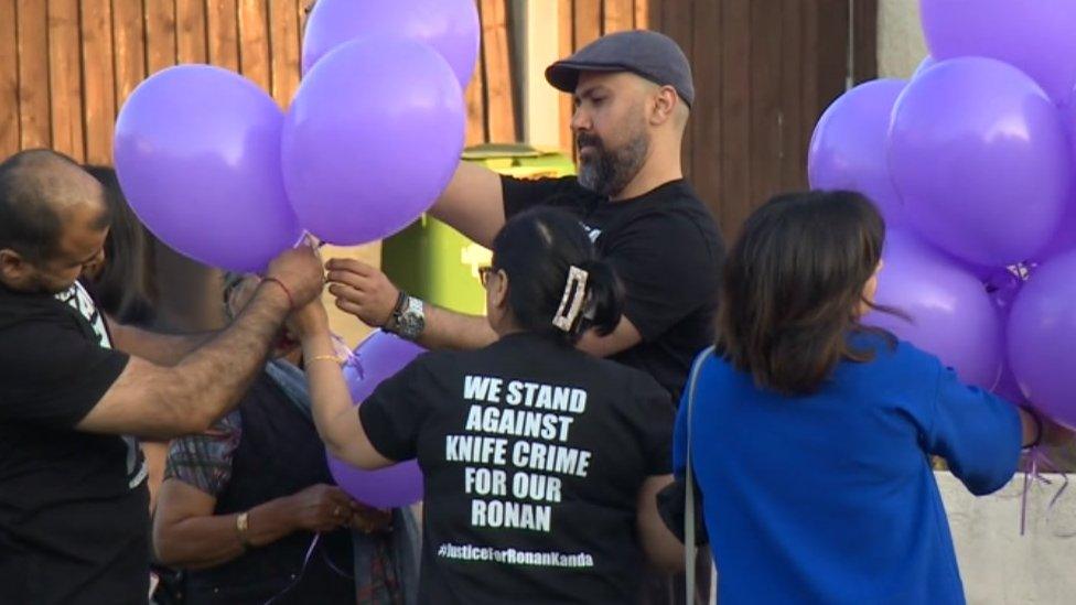 People holding purple balloons